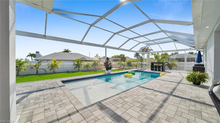 Outdoor pool with glass enclosure, a sunroom, a patio, and a fenced backyard