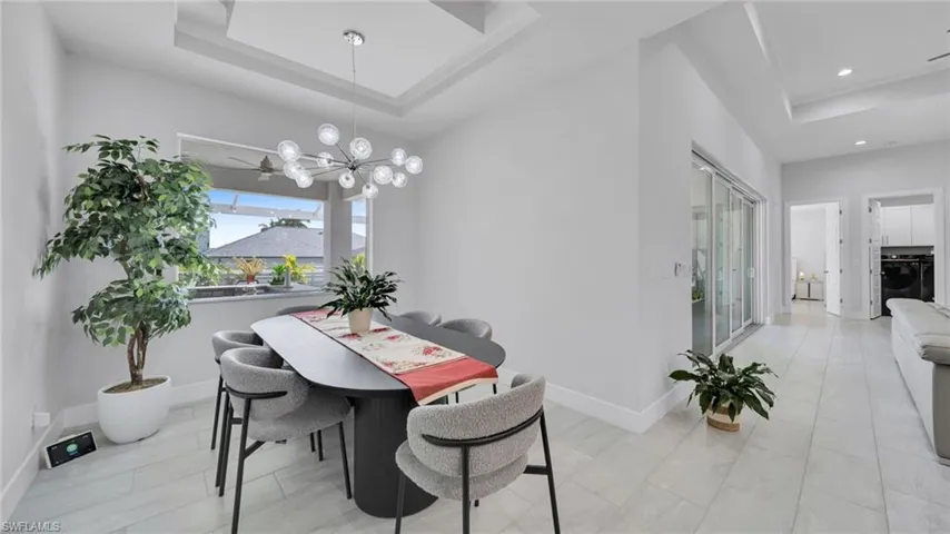 Dining space featuring a tray ceiling, a chandelier, washer / clothes dryer, and recessed lighting