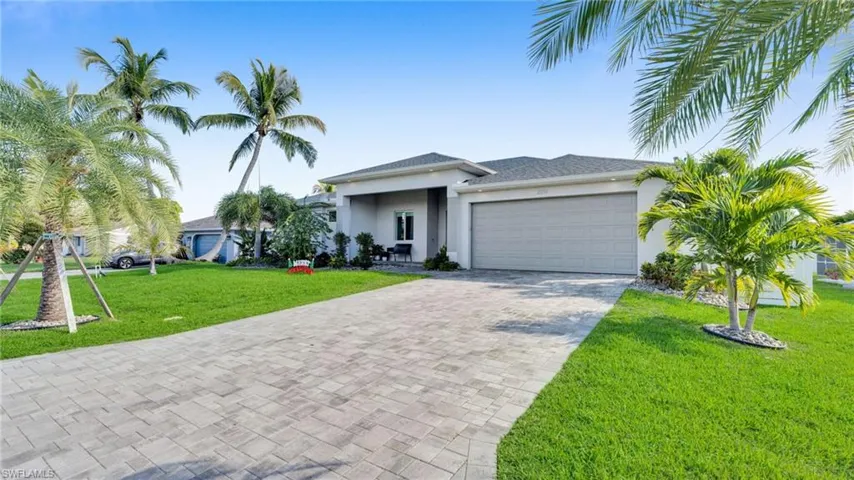 View of front of home featuring a front yard, stucco siding, decorative driveway, and an attached garage
