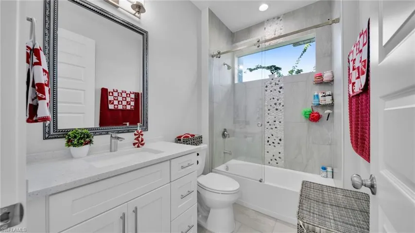 Bathroom with shower / bath combination with glass door and vanity