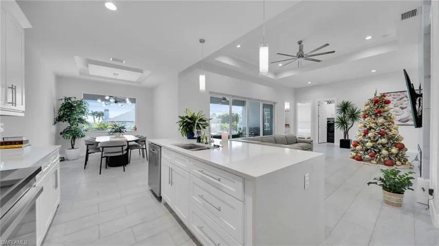 Kitchen featuring a raised ceiling, white cabinetry, and a ceiling fan