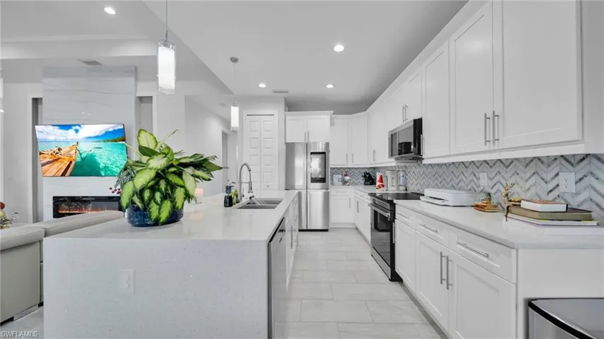 Kitchen featuring pendant lighting, stainless steel appliances, light stone counters, recessed lighting, and white cabinetry