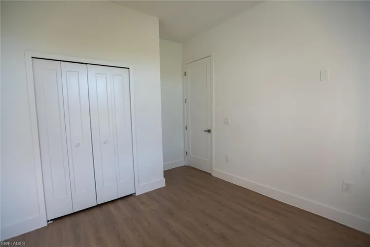 Unfurnished bedroom featuring dark wood-type flooring and a closet