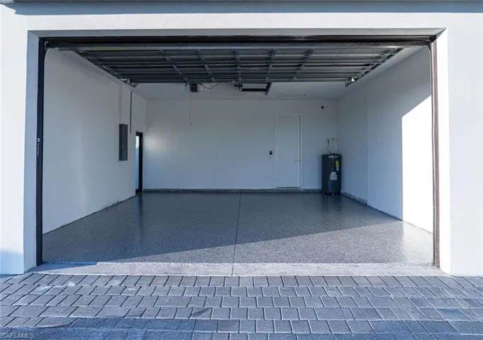 Garage featuring water heater, a garage door opener, and electric panel