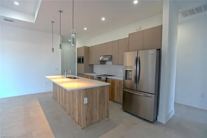 Kitchen featuring sink, a kitchen island with sink, hanging light fixtures, stainless steel appliances, and tasteful backsplash