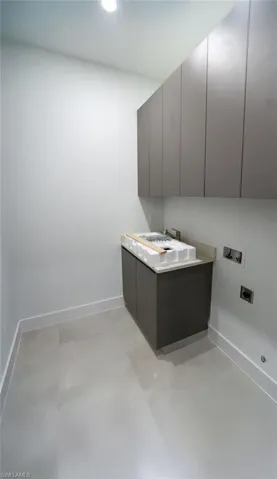Washroom featuring electric dryer hookup, hookup for a washing machine, and cabinets