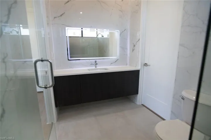 Bathroom featuring vanity, a shower with shower door, and toilet