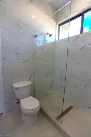 Bathroom with tile patterned floors, toilet, and a tile shower