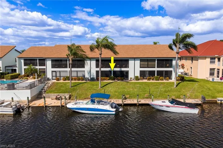 Waterfront multi-story building featuring a dock with boat slips and direct water access