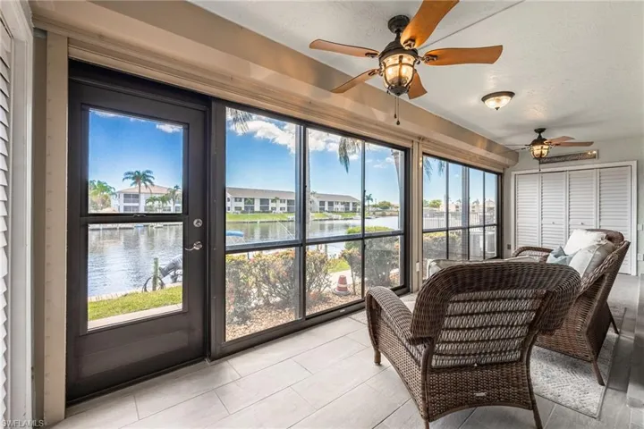 Enclosed sunroom featuring full-height glass panels, a single access door, two ceiling fans with light kits, and light-toned tile flooring