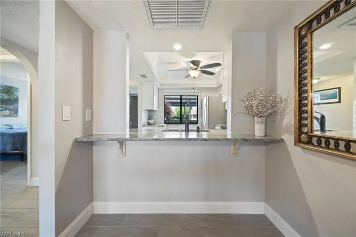Kitchen pass-through window with a light-toned countertop, extending into a built-in shelf