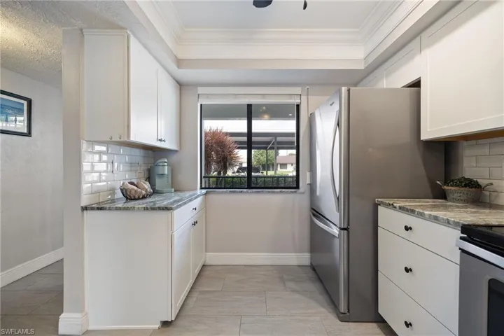 Kitchen featuring white shaker-style cabinetry, a subway tile backsplash, and granite countertops