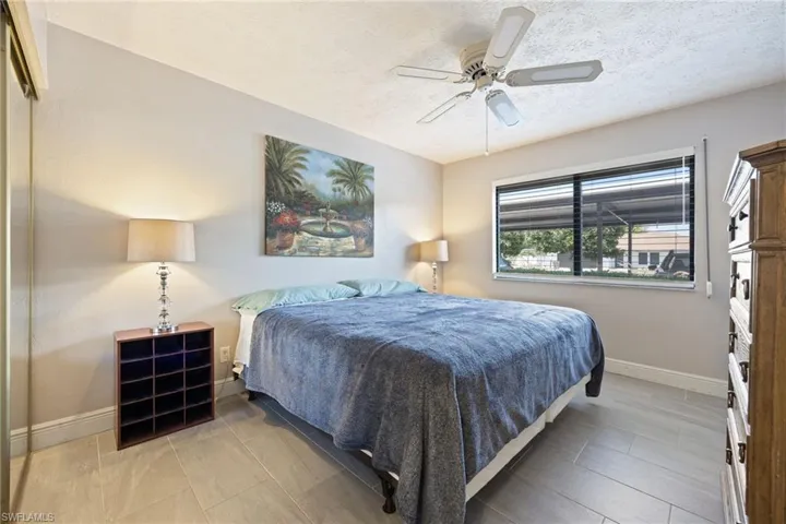Bedroom featuring light gray wall paint, wood-finish flooring, a ceiling fan with integrated lighting, and a window with horizontal blinds