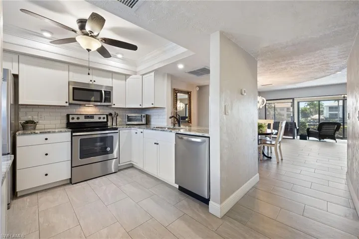 Kitchen featuring white cabinetry, stainless steel appliances, subway tile backsplash, and light-toned tile flooring