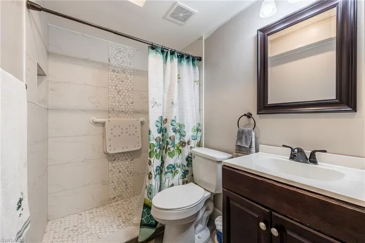 Bathroom featuring a stand-up shower with white subway tile and hexagonal mosaic tile accents