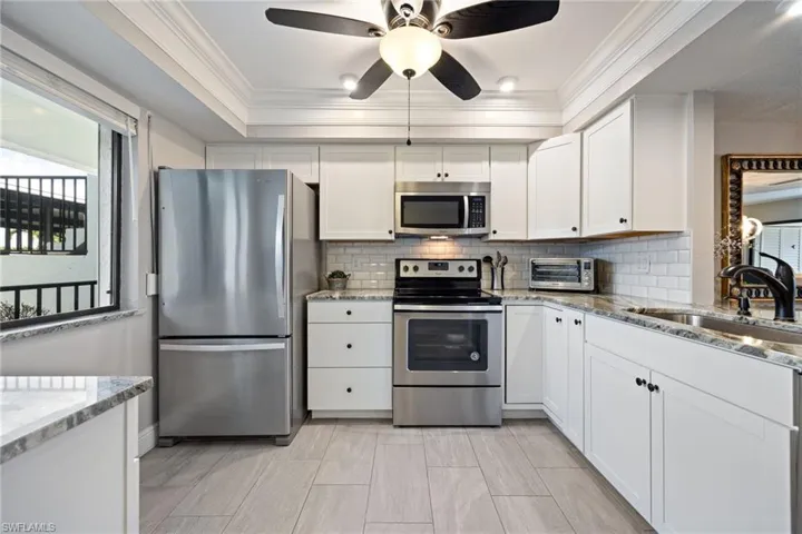 Well-appointed kitchen featuring white cabinetry, stainless steel appliances, and light-toned tile flooring