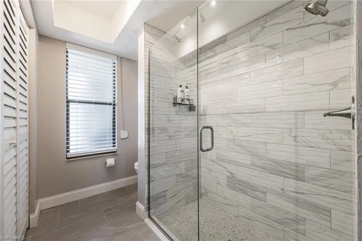 Frameless glass shower with large format tile walls and pebble floor