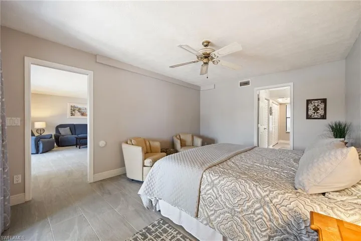 Spacious room featuring light gray walls, wood-finish flooring, and a ceiling fan with integrated lighting