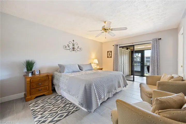 Spacious room featuring tile flooring, ceiling fan, and sliding glass doors opening to an outdoor area