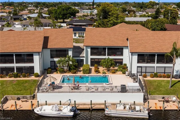 Waterfront property featuring a private pool area, multiple boat docks, and a paved patio