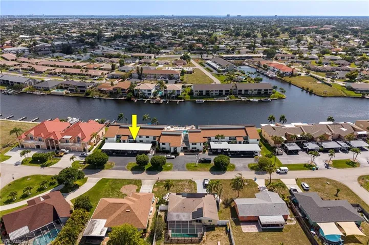Waterfront condominium building featuring a private boat dock, covered parking, and mature palm trees