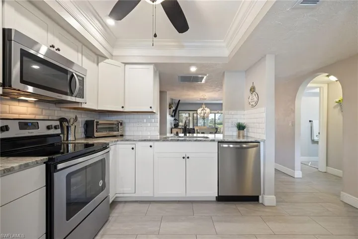 Kitchen featuring white cabinetry, subway tile backsplash, stainless steel appliances, and stone countertops