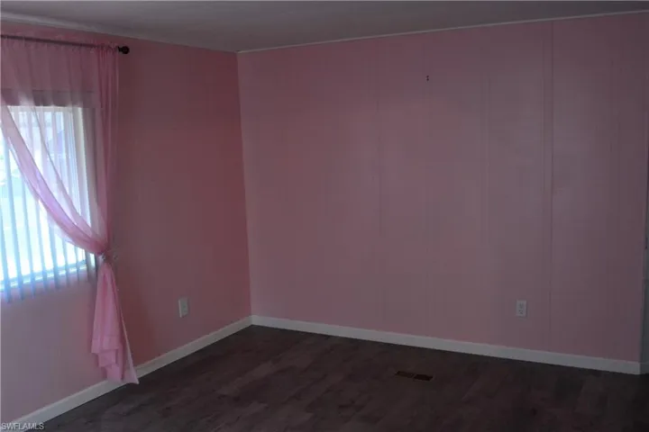 Empty room featuring dark wood-type flooring and baseboards