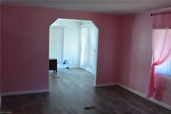 Spare room featuring dark wood-type flooring and baseboards