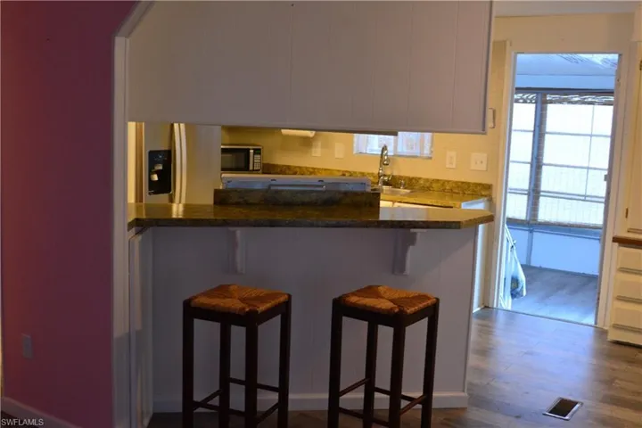 Kitchen with a breakfast bar, stainless steel appliances, dark wood-type flooring, and white cabinets