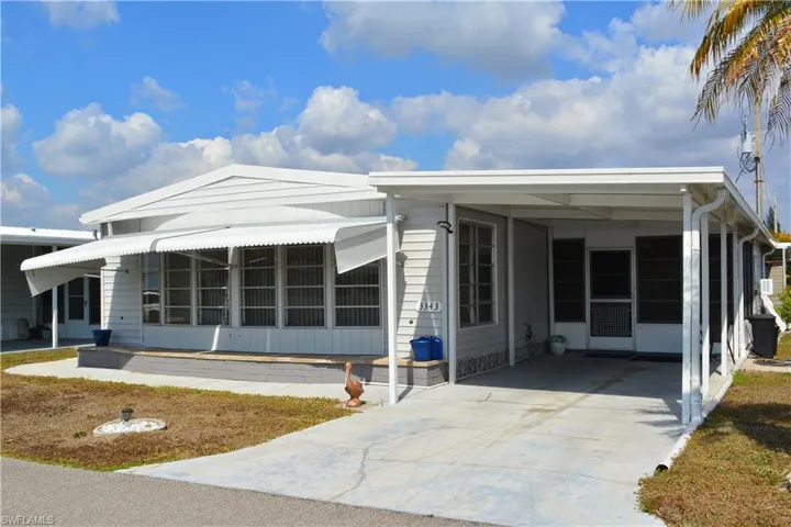 View of front facade with driveway, a sunroom, and a carport