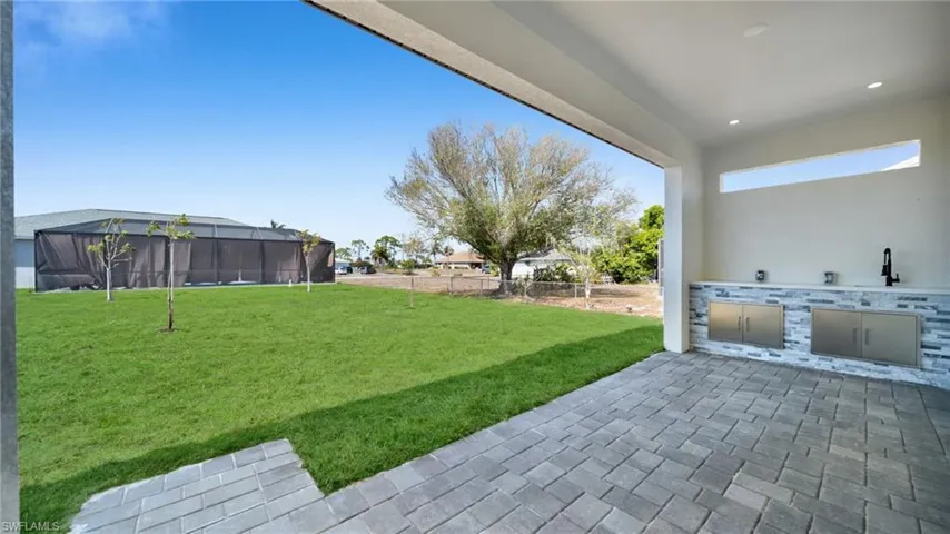 Fenced yard with an outdoor kitchen, a lanai, and a patio area