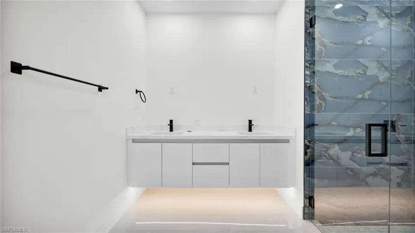 Bathroom with double vanity and a marble finish shower