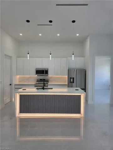Kitchen with white cabinetry, hanging light fixtures, and modern cabinets