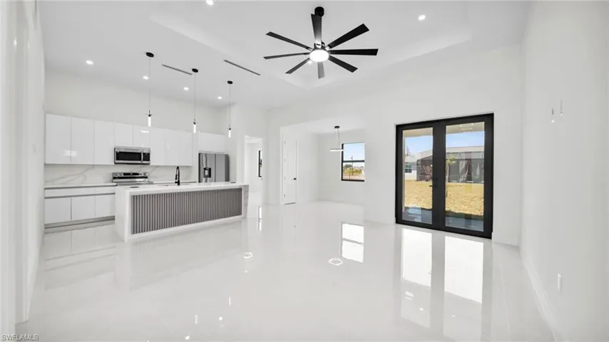 Kitchen with white cabinets, decorative light fixtures, modern cabinets, french doors, and a kitchen island with sink