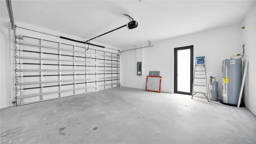 Garage featuring water heater, electric panel, and a garage door opener