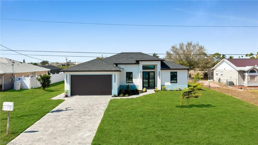 View of front of home featuring a shingled roof, stucco siding, decorative driveway, and a garage