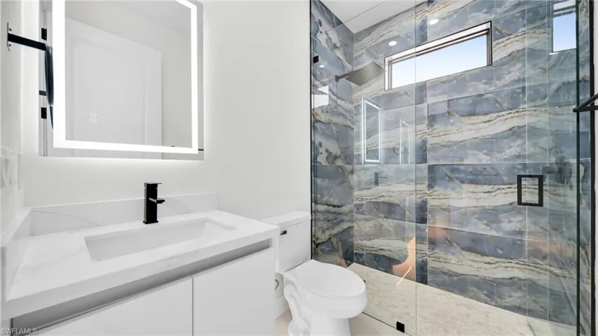 Full bath featuring vanity and a marble finish shower