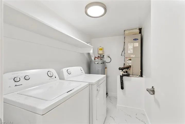 Laundry room with washing machine and dryer, heating unit, light marble finish floors, and water heater