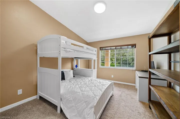 Bedroom with light carpet and lofted ceiling