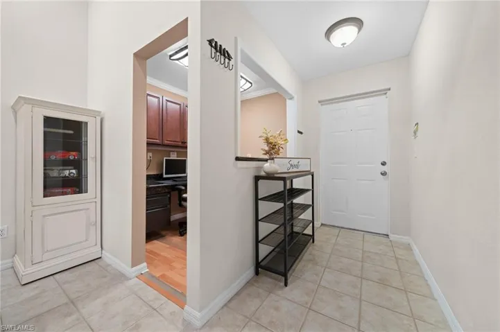 Entrance foyer with light tile patterned flooring, built in desk, and ornamental molding