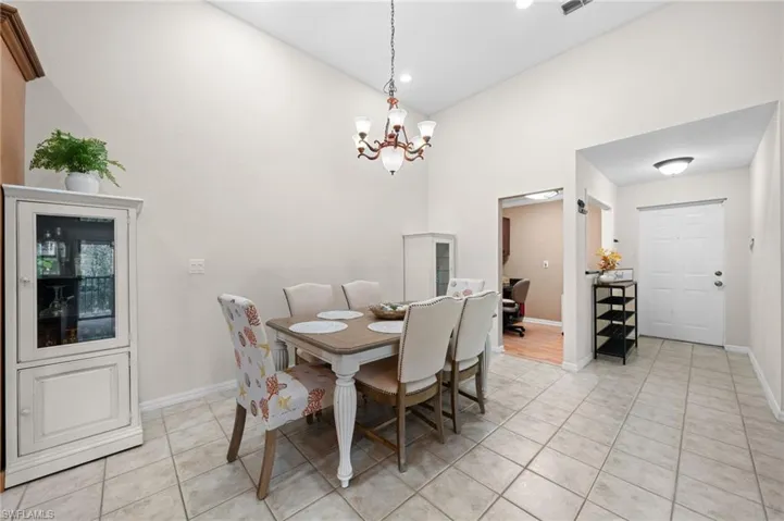 Tiled dining room with a notable chandelier and a towering ceiling
