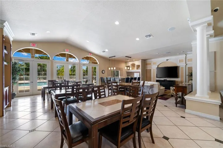 Tiled dining space featuring french doors, vaulted ceiling, a textured ceiling, and decorative columns