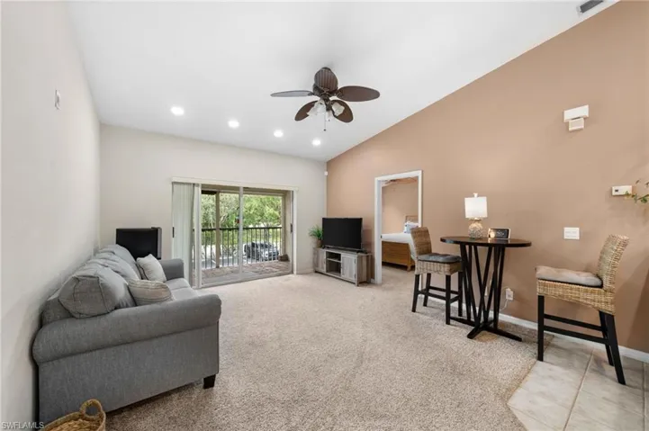 Living room with ceiling fan, light carpet, and vaulted ceiling