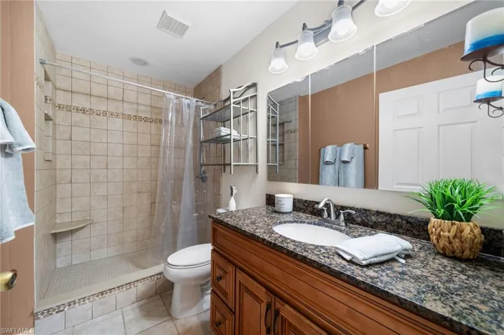Bathroom with vanity, tile patterned flooring, toilet, and a shower with shower curtain