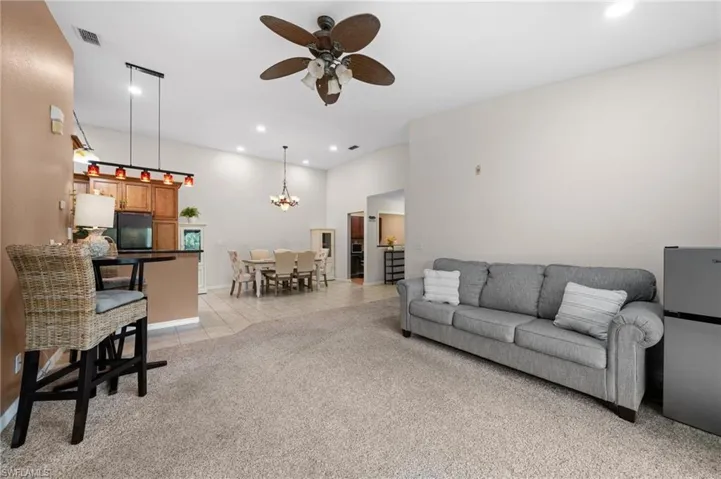 Tiled living room featuring ceiling fan with notable chandelier