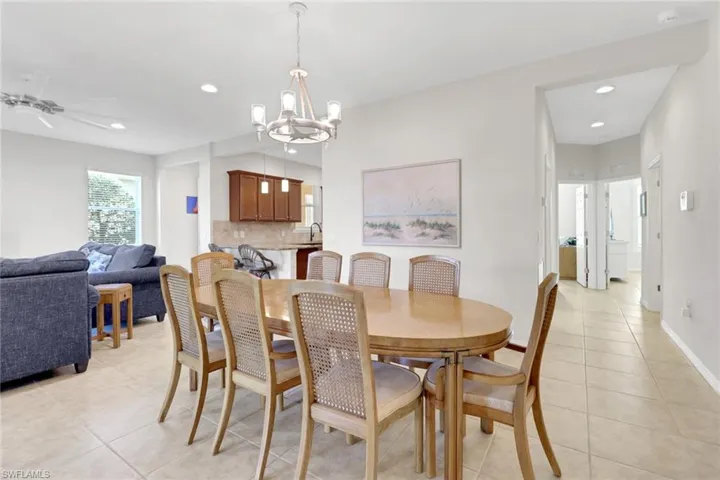 Dining area with light tile patterned floors, ceiling fan with notable chandelier, and sink