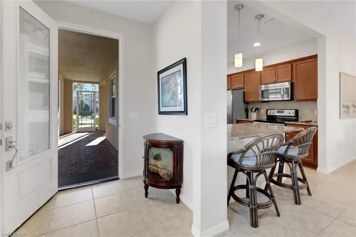 Kitchen featuring decorative backsplash, a kitchen breakfast bar, stainless steel appliances, light tile patterned floors, and decorative light fixtures