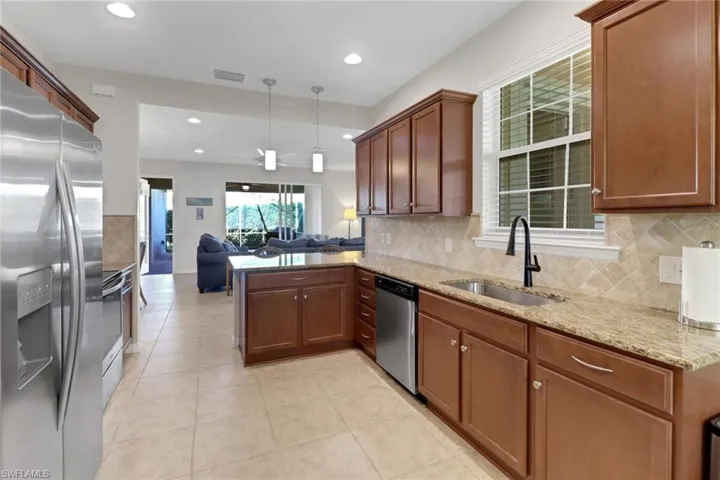 Kitchen featuring sink, ceiling fan, appliances with stainless steel finishes, decorative light fixtures, and kitchen peninsula