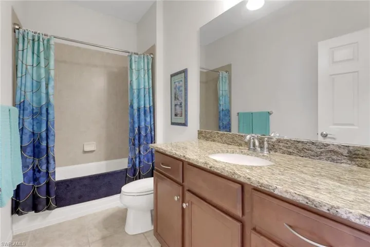 Full bathroom with tile patterned floors, vanity, shower / tub combo, and toilet