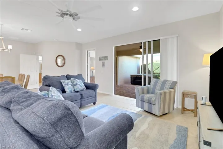 Living room with ceiling fan with notable chandelier and light tile patterned floors